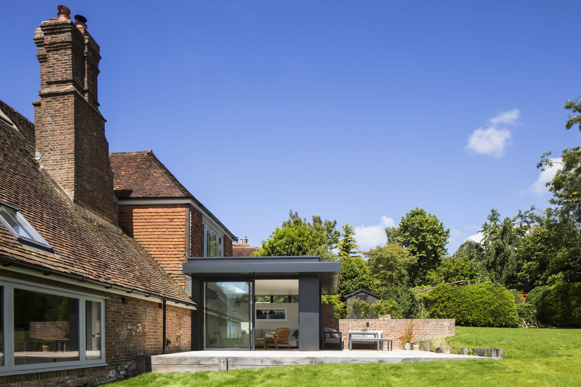 Heritage residential conversion in Sussex, featuring brick house, patio, and lawn. Stickland Wright Architecture and Interior Design