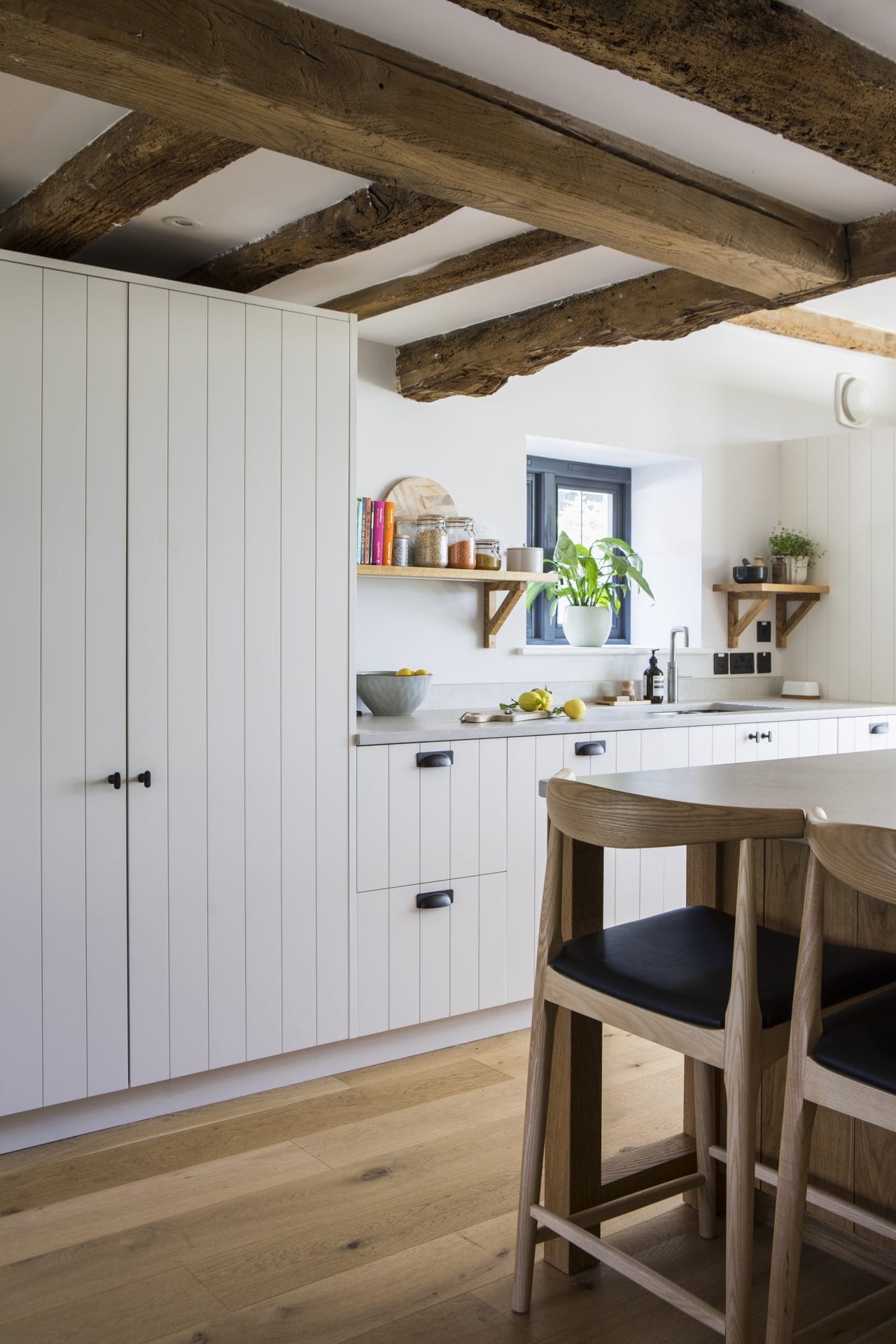 Interior of Sussex residential conversion featuring kitchen with islane table and chairs. Stickland Wright Architecture and Interior Design